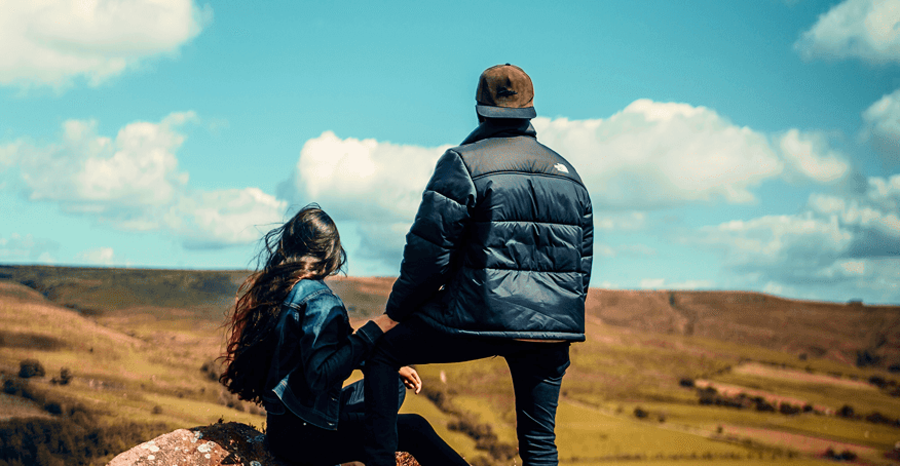 丘の上で二人が景色を眺めるイメージ