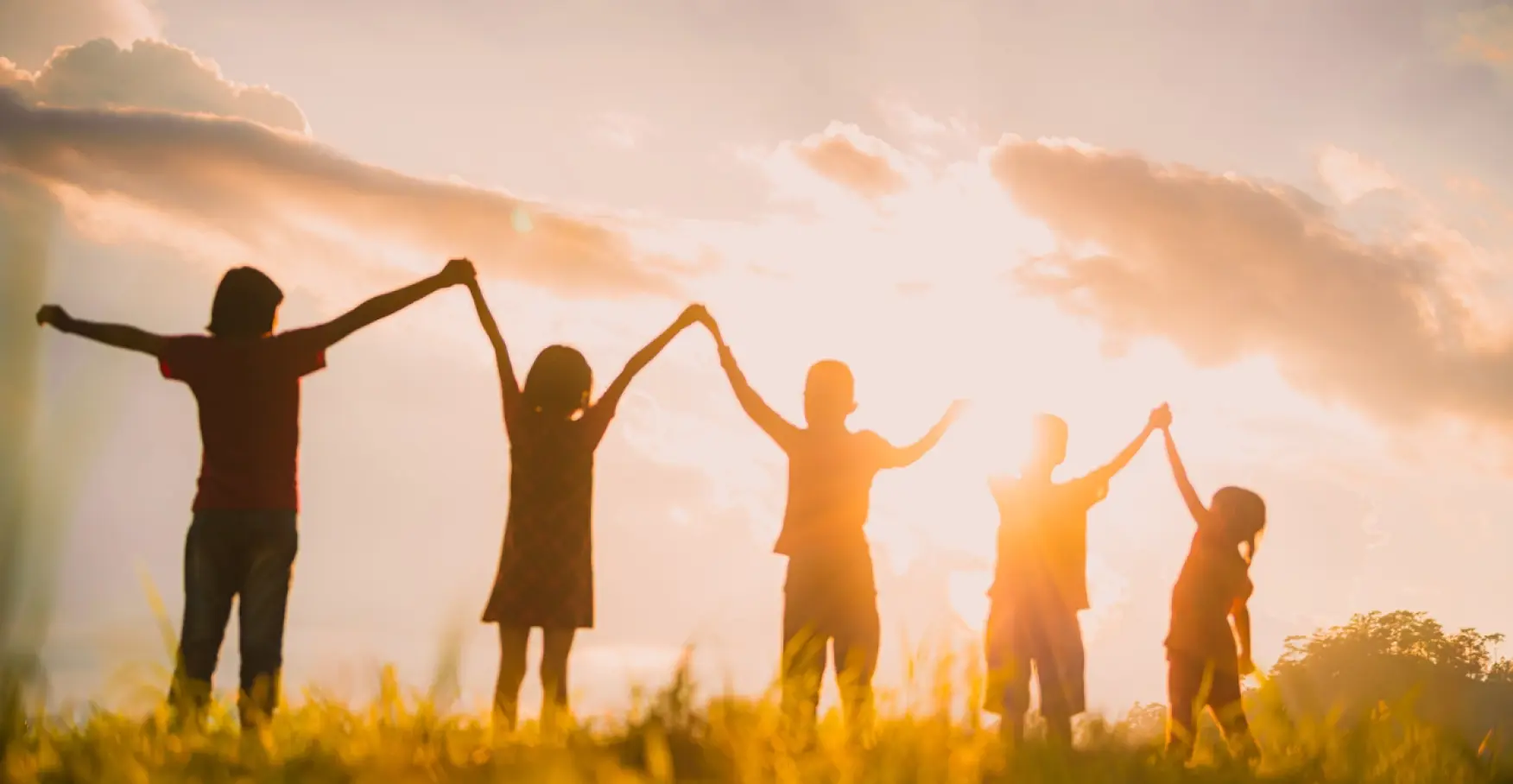 夕日の中手をつなぎ合う子供たちのイメージ