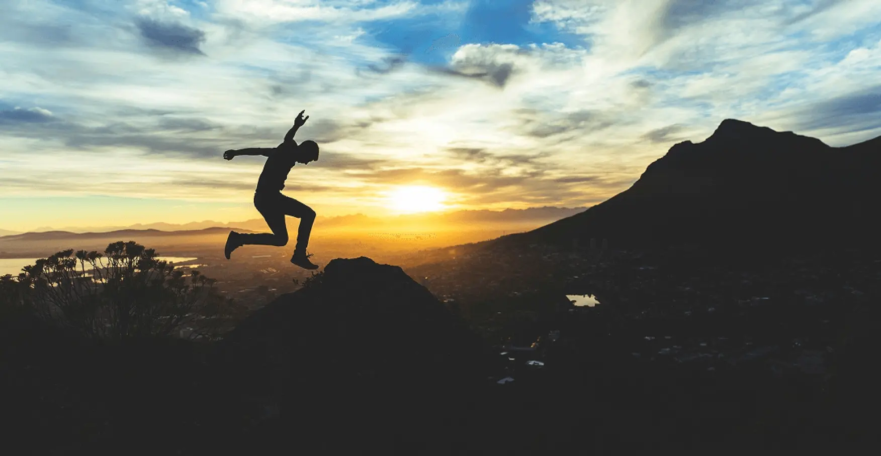 夕陽を背景に、岩場から力強く飛び出す人物のイメージ