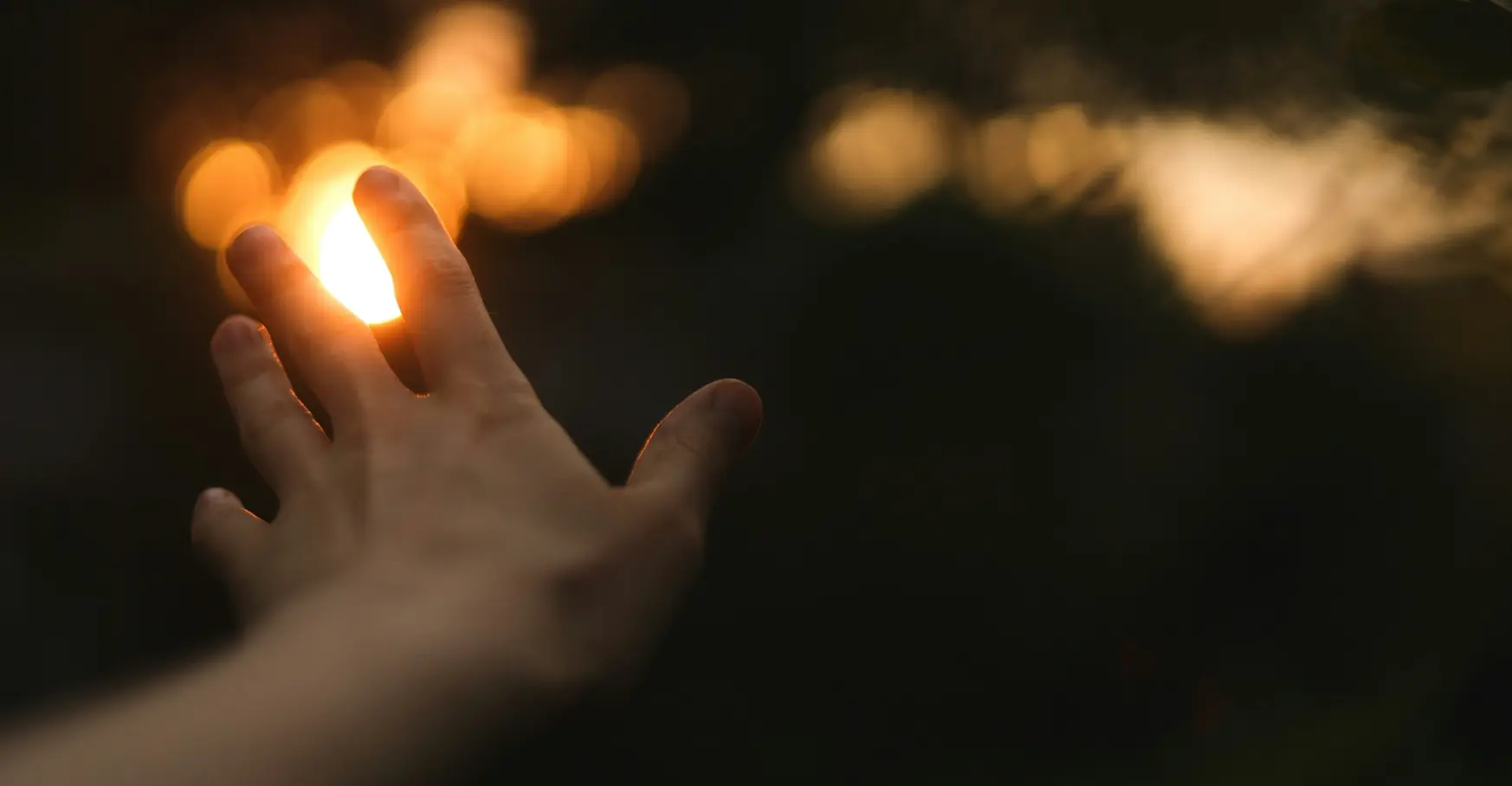 指の間から溢れる明るい夕日の光と差し出された左手