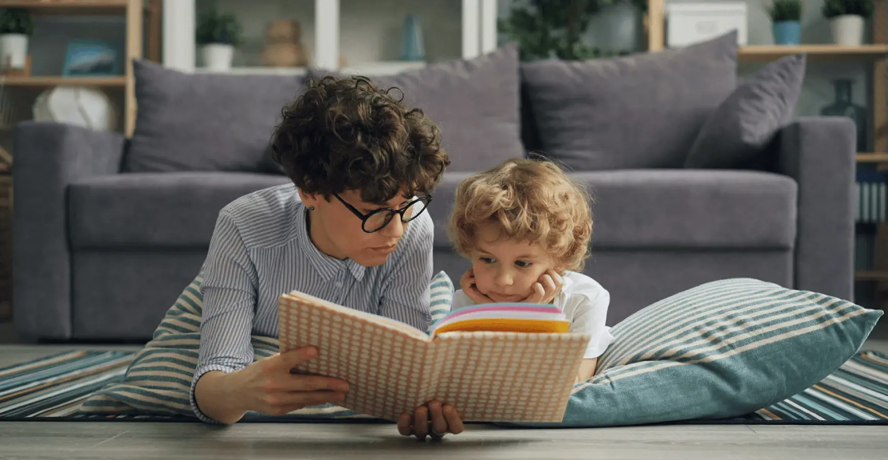 室内で大人と子どもが並んで本を読むイメージ