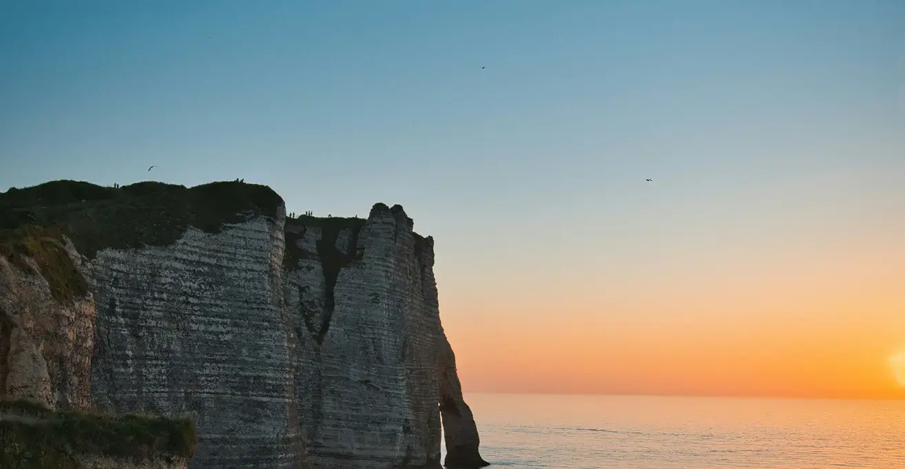 フランスのエトルタを思わせる断崖絶壁と、穏やかな海に沈みゆく美しい夕日