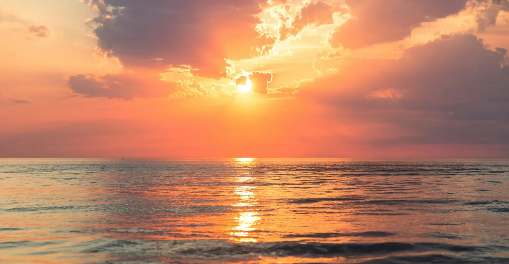 水平線に沈む夕陽が海面を照らす瞬間