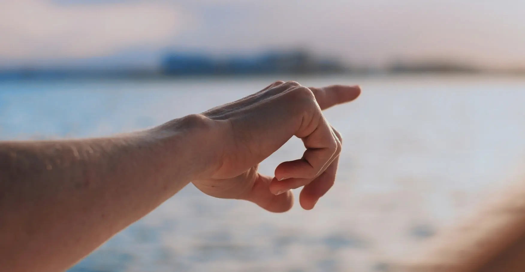 海辺で指先が前方を示すイメージ