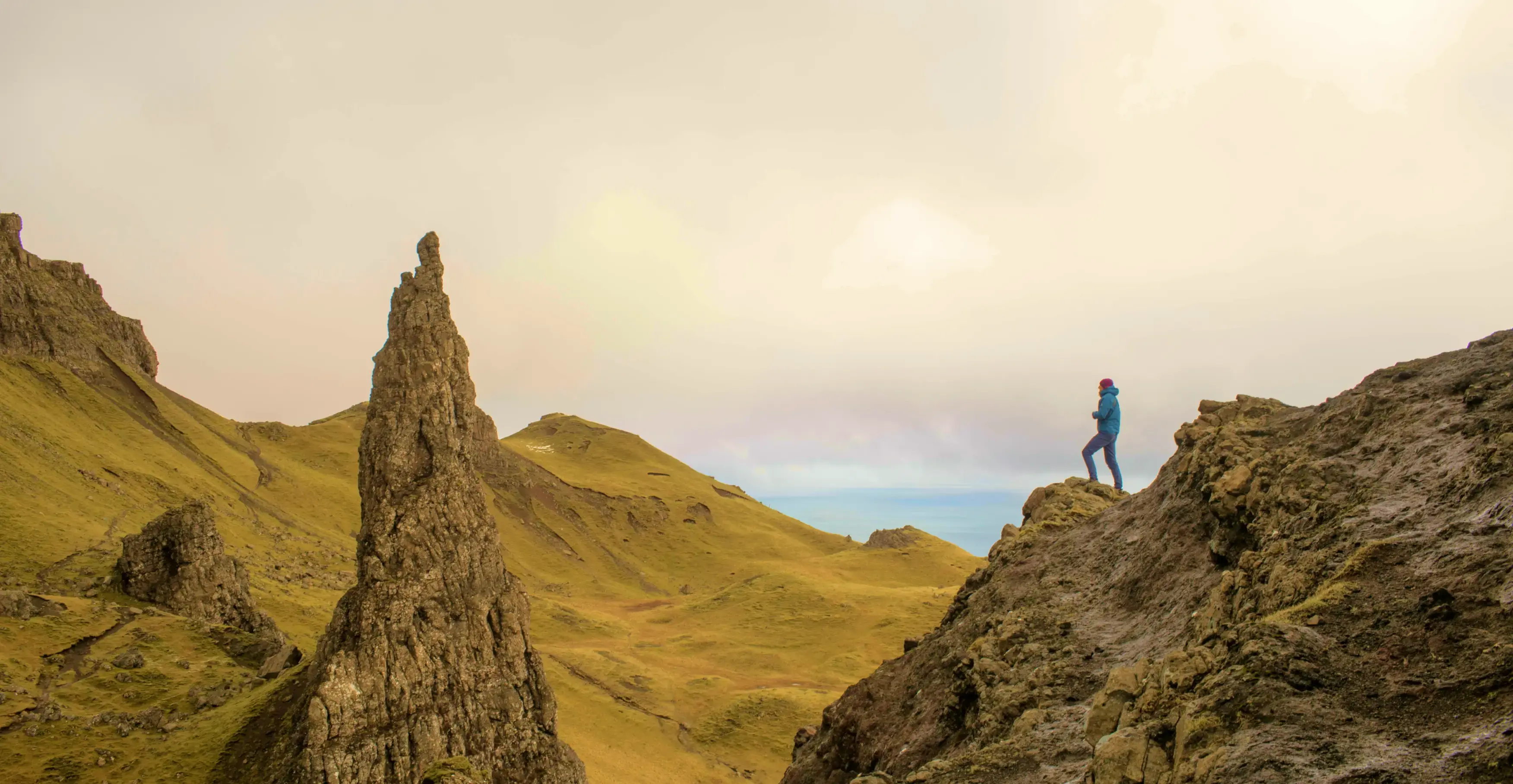切り立った岩山がそびえる高地で、景色を眺めるハイカーの姿