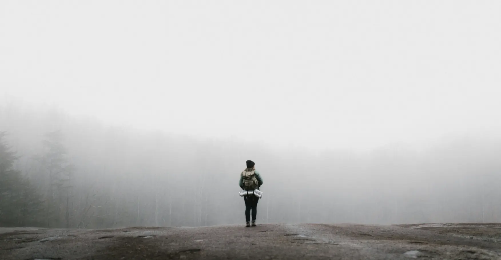 霧の中で佇むバックパック姿の人物のイメージ