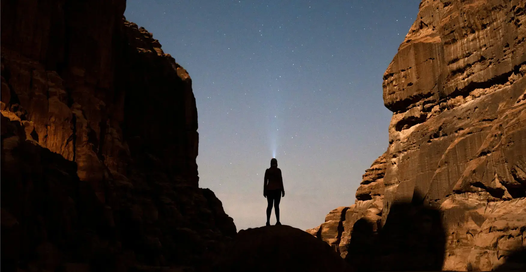 星空の下、峡谷でライトを空に向ける人のシルエット