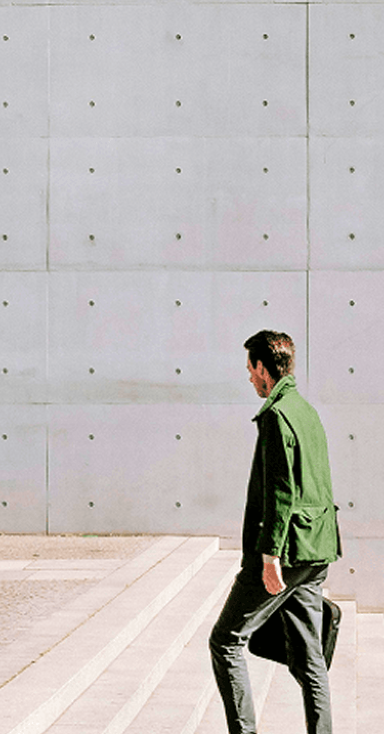 コンクリートの広場で男性が一人歩くイメージ