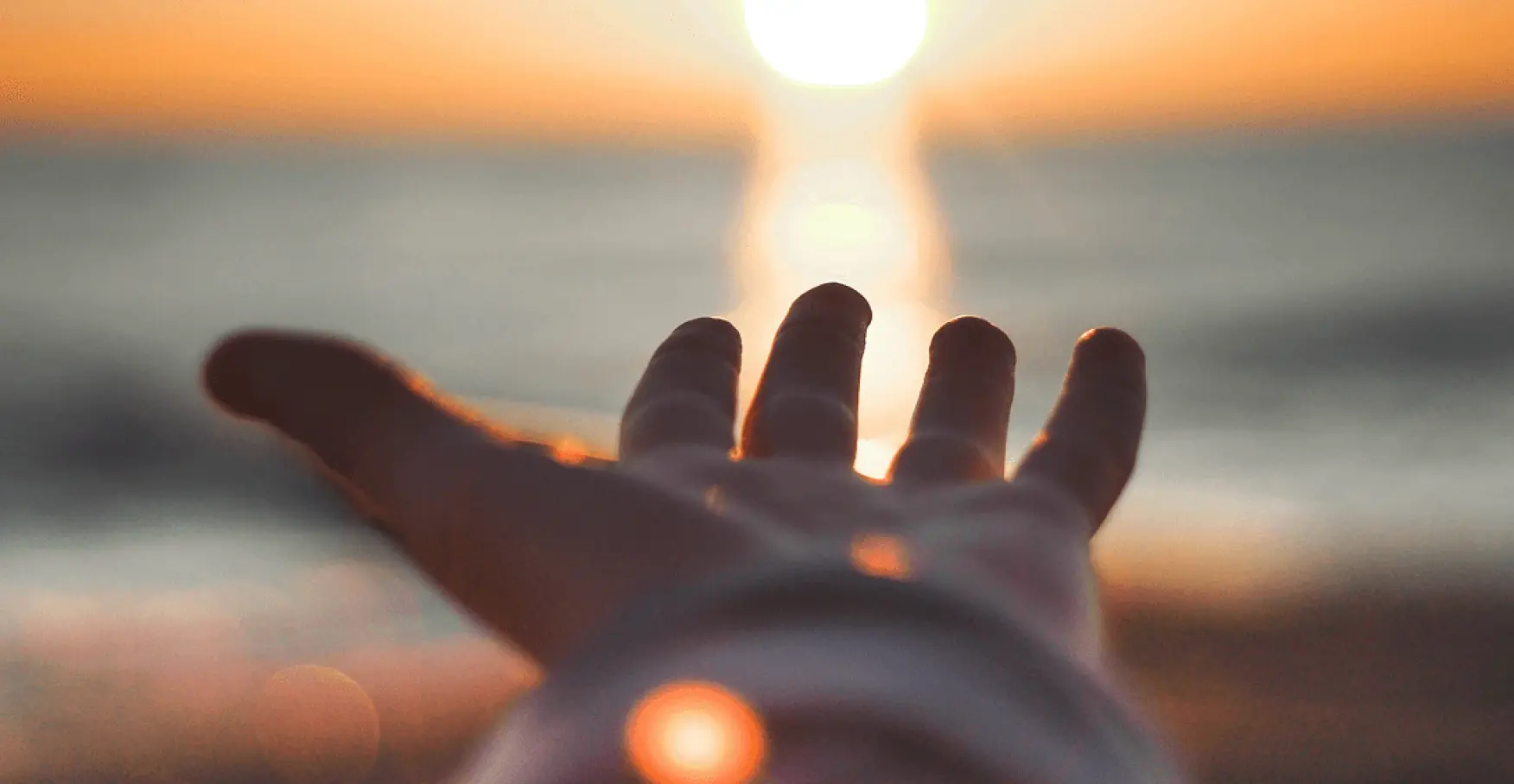 夕日に向かって手を伸ばすイメージ