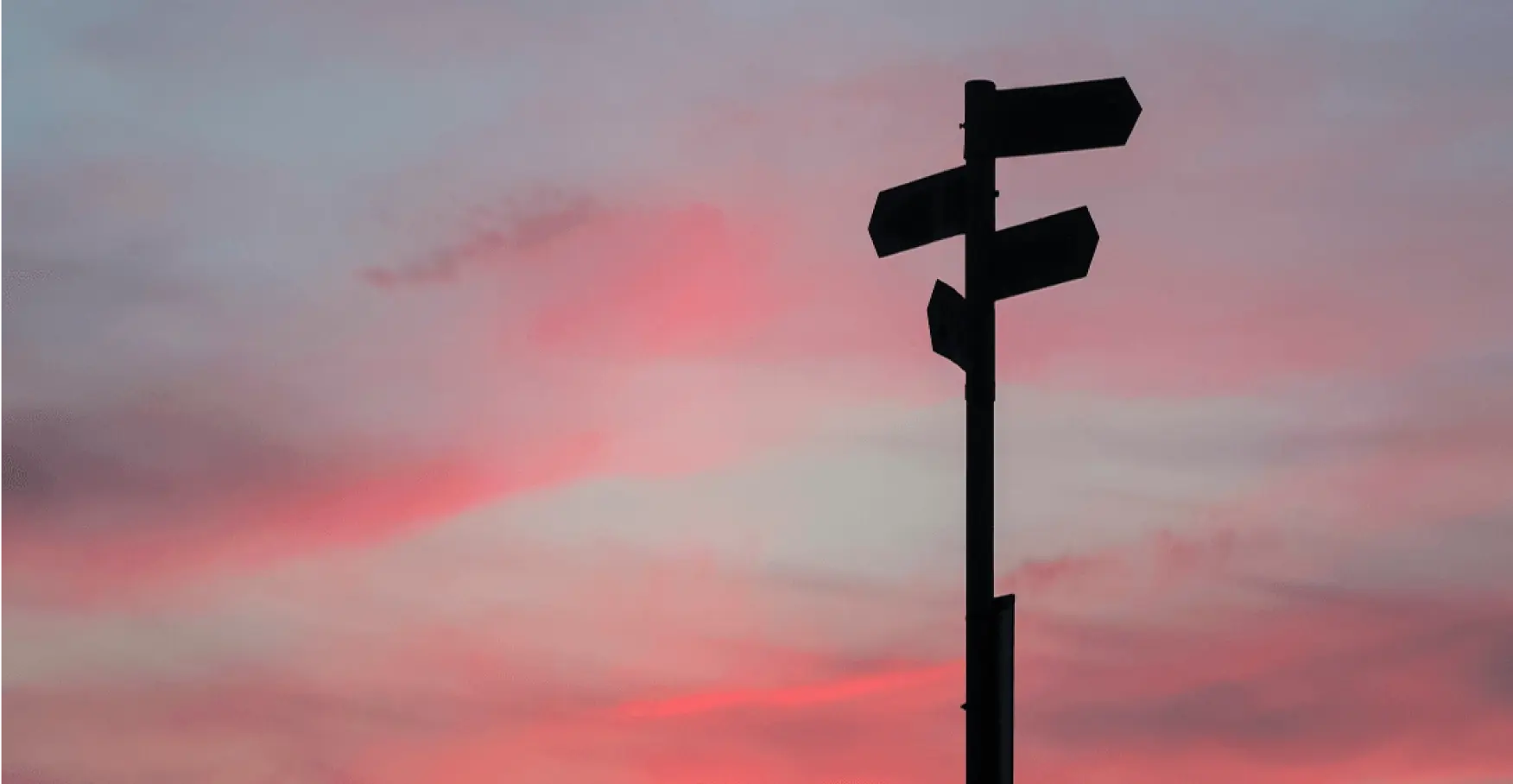 夕焼け空に立つ分岐案内のサインポールのイメージ