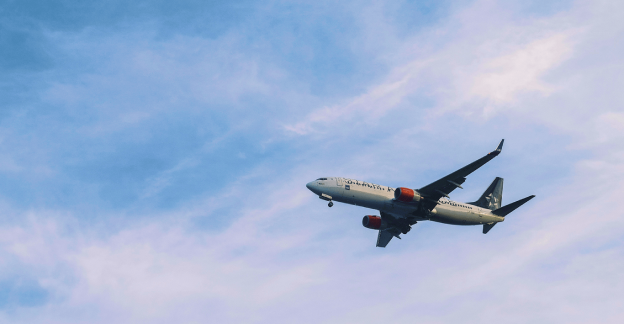 青空の中を飛ぶ飛行機のイメージ